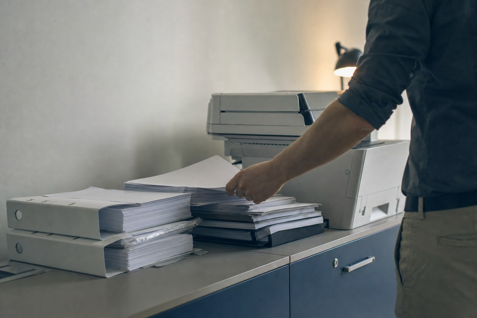 Stos wydruków i segregatorów przy kopiarce biurowej